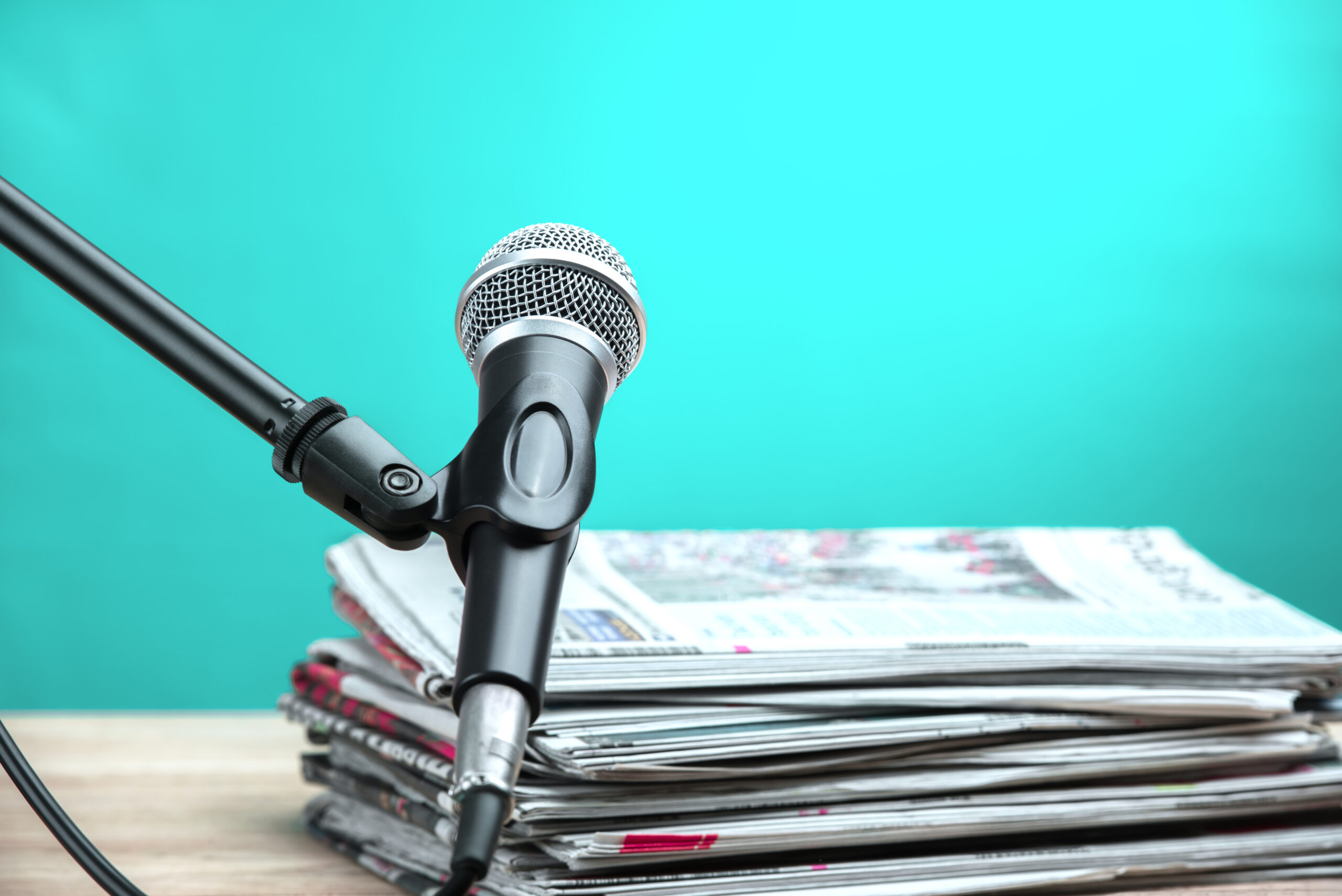 Microphone with newspaper on wooden table - announcement concept